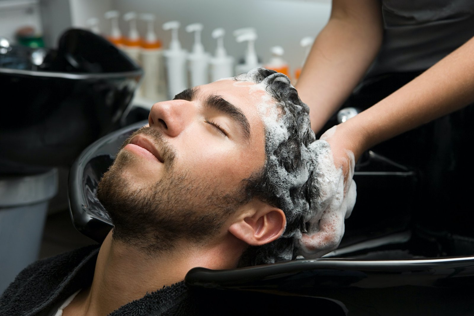 Hun masserer så forsiktig shampooen inn i håret til mannen, og sørger for å dekke alle områder fra hodebunnen til tuppene. shampoo og balsam