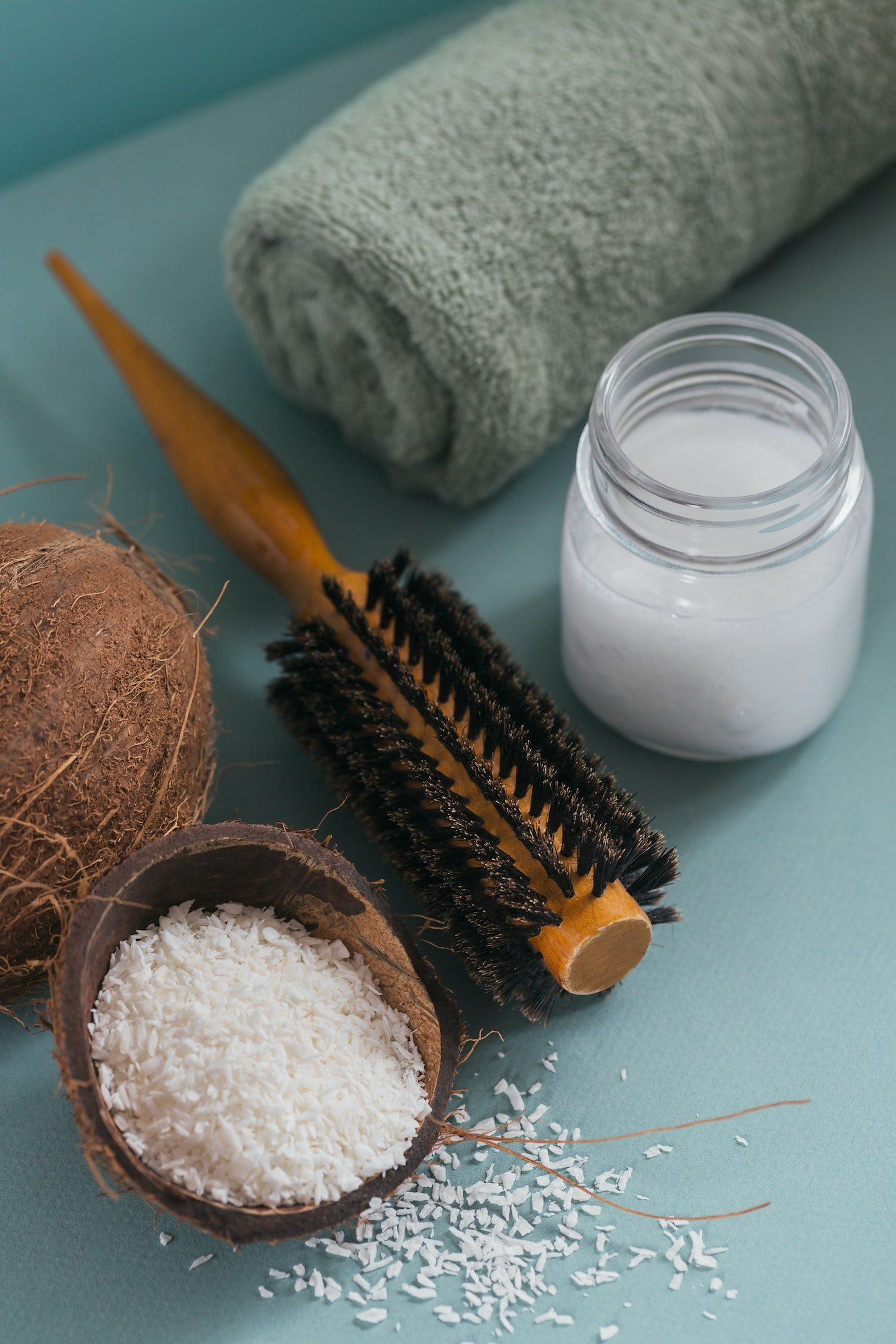 Coconut oil in a bottle with coconuts, towel and hairbrush