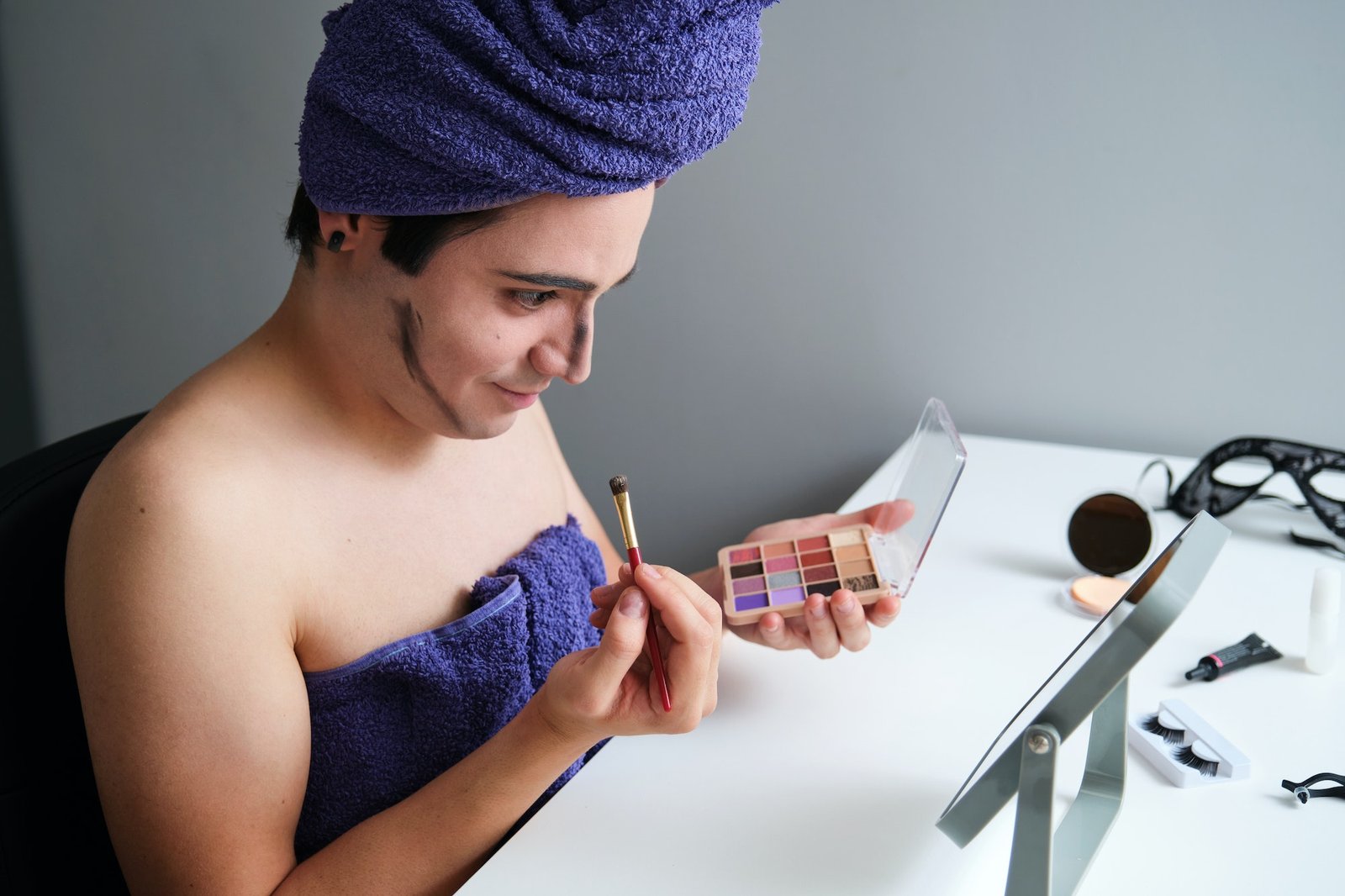 Ung transkjønnet mann konturerer ansiktet sitt etter dusjen.