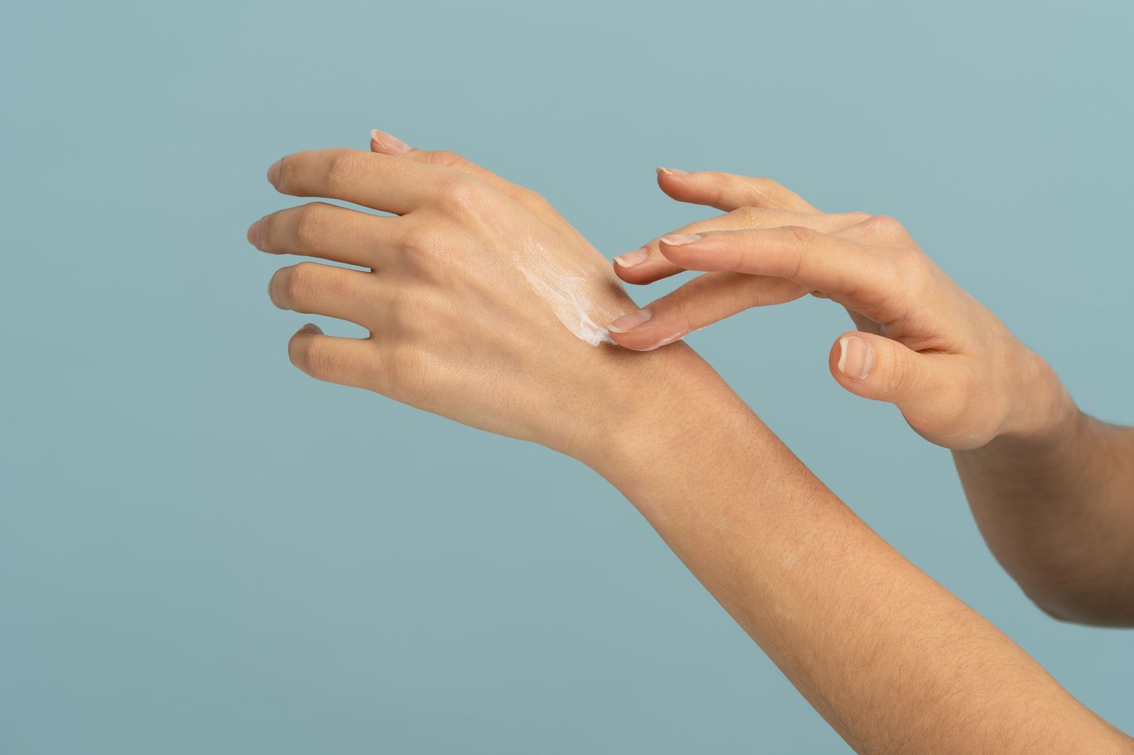Woman applying protective cream on dry skin of hands in cold season, isolated